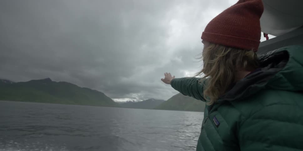 A man is pointing out towards the mountain on a boat