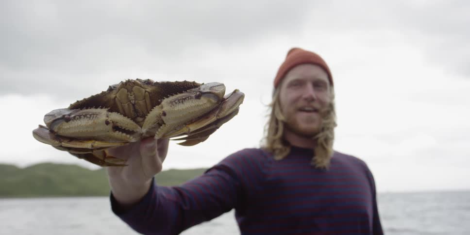 A man holds a crab on a boat
