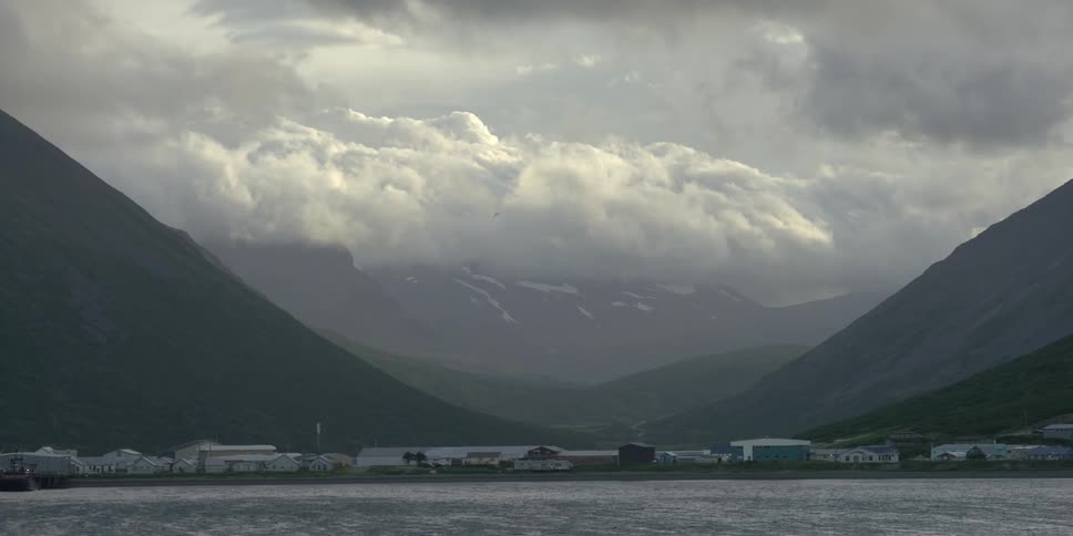 Clouds hang above a mountain and coastal town
