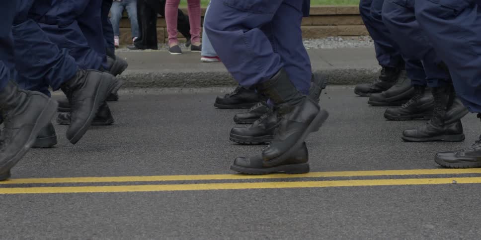 Soldiers march together on a street