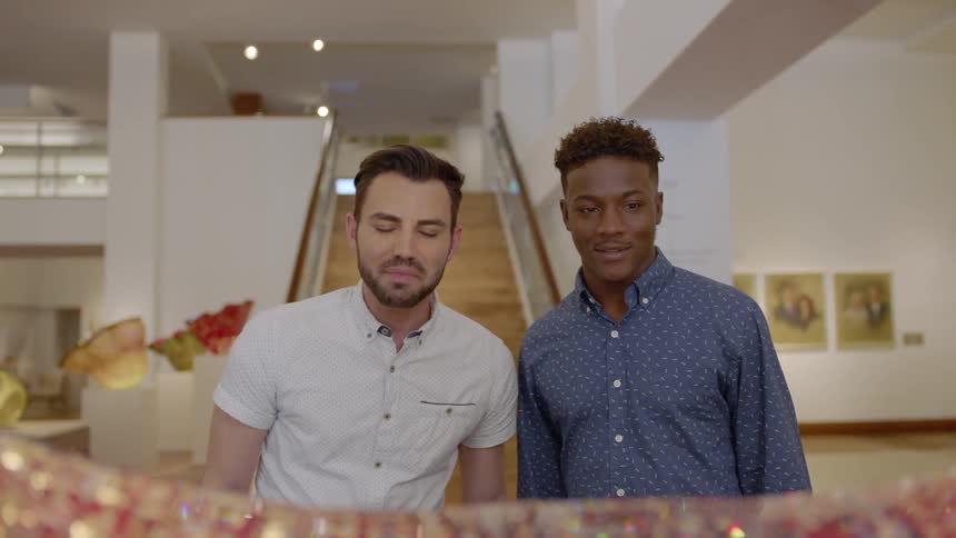Two men look at a piece of art in a museum