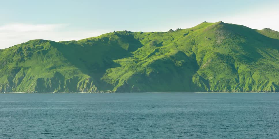 A green island is surrounded by calm water on a sunny day