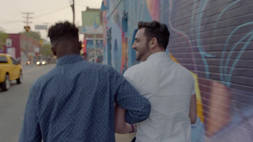 Two men walk down the street arm in arm
