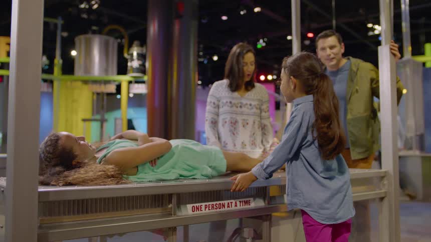 A girl lies on a table in a science museum
