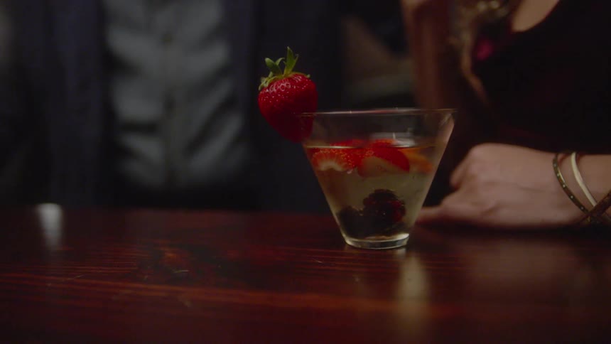 A woman drinks a cocktail at a bar counter