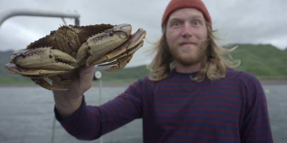 Man holds a crab on a fishing boat