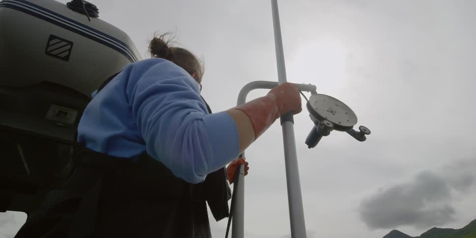 Someone is standing on the deck of a boat watching as a winch pulls in some rope