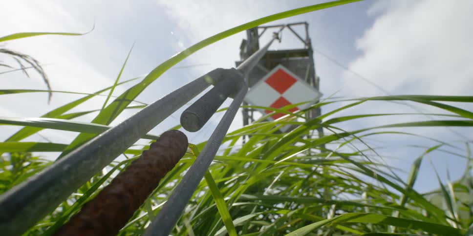 A cable secures a metal tower in a field