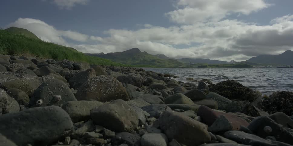 The waves crash against the rocks on the shore
