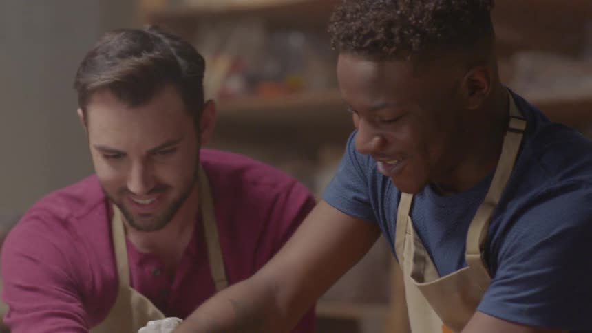 Two men laugh while doing pottery