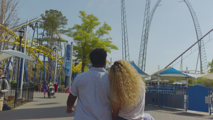 Man and woman hold hands in an amusement park