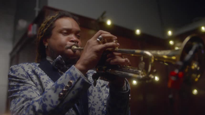 A man is playing a trumpet in a club at night