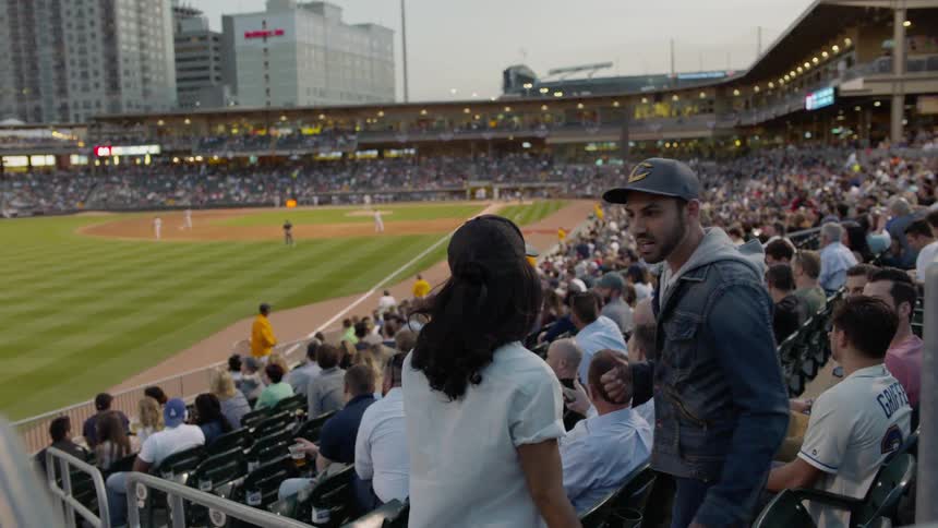A man and woman find seats at a baseball game