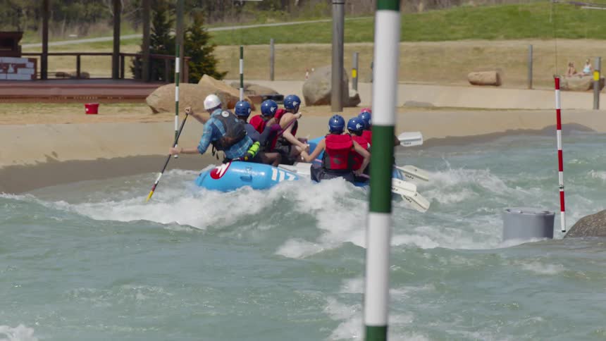 People are navigating a raft over rapids in a waterpark