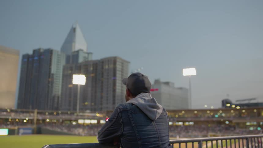 A man is looking out over the baseball stadium