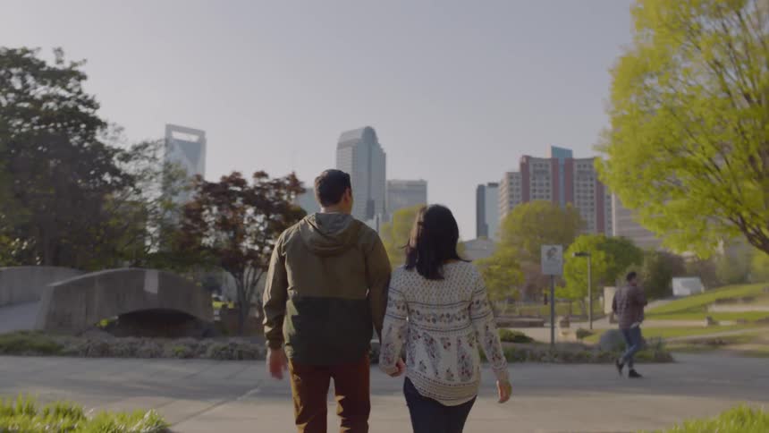 Man and woman hold hands while walking on a city sidewalk