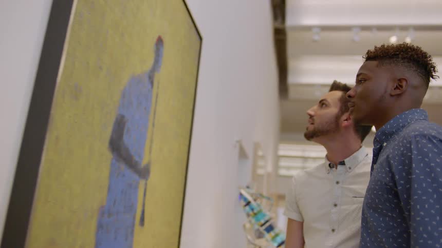 Two men look at a painting on the wall