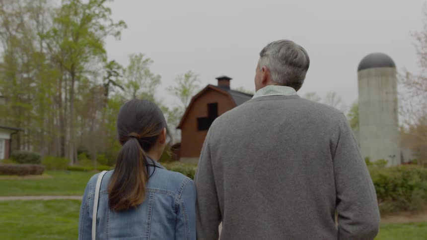 A man and woman are walking toward a large cross in a park on a cloudy day