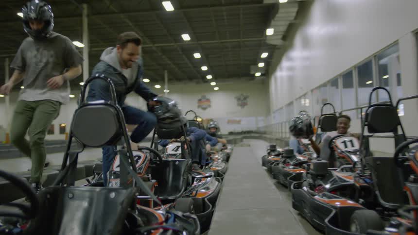 People climb into go-karts on an indoor track