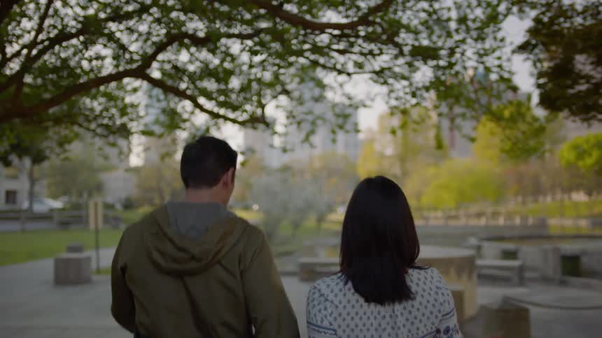 Man and woman hold hands walking over a bridge made of concrete