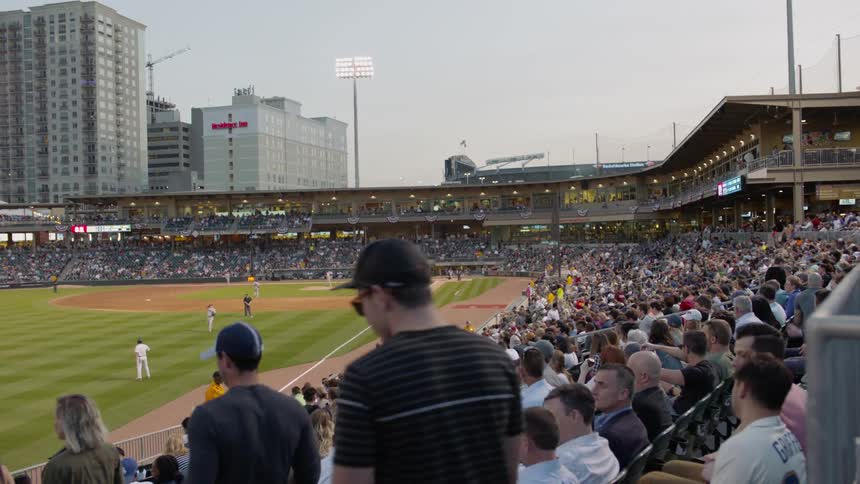 People walk to their seats in a ballpark
