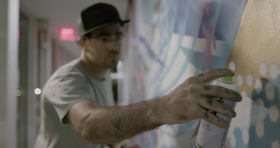 A man spray paints dots onto a wall