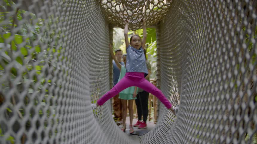 A kid is climbing and making her way through a net