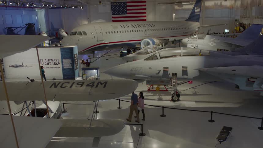 People walk around and look at planes in a hangar museum
