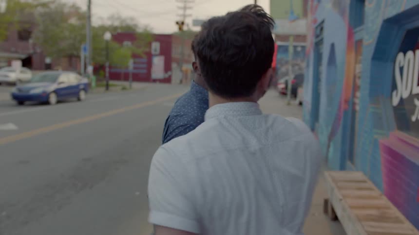 A couple looks at murals as they walk down the sidewalk