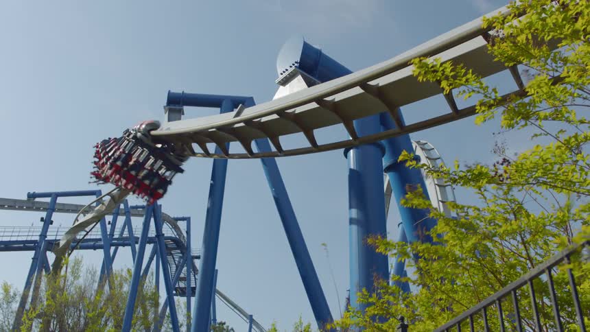 People ride on a twisting roller coaster on a sunny day