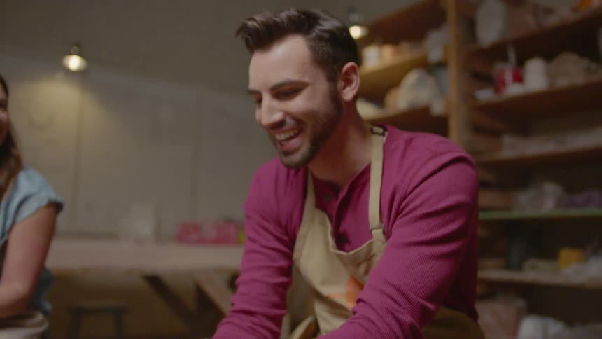 Man smiles while working at a pottery wheel