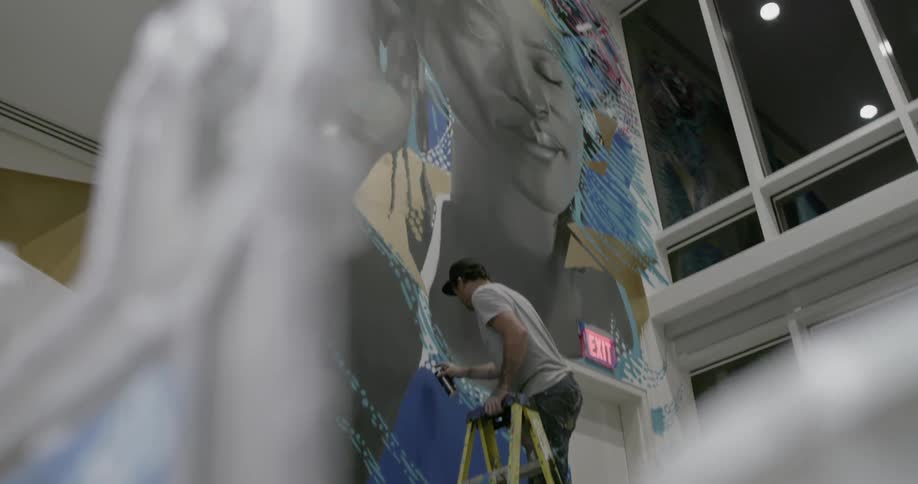 A man is painting the tall wall in the building