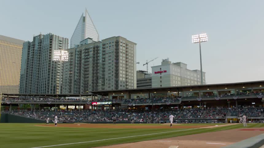 Baseball players play on a field in the middle of a city