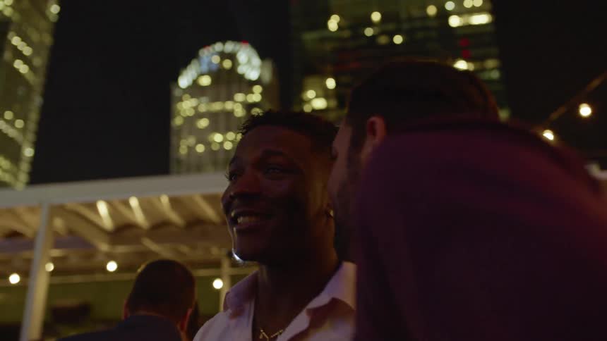 Two men dance and talk at an outdoor party