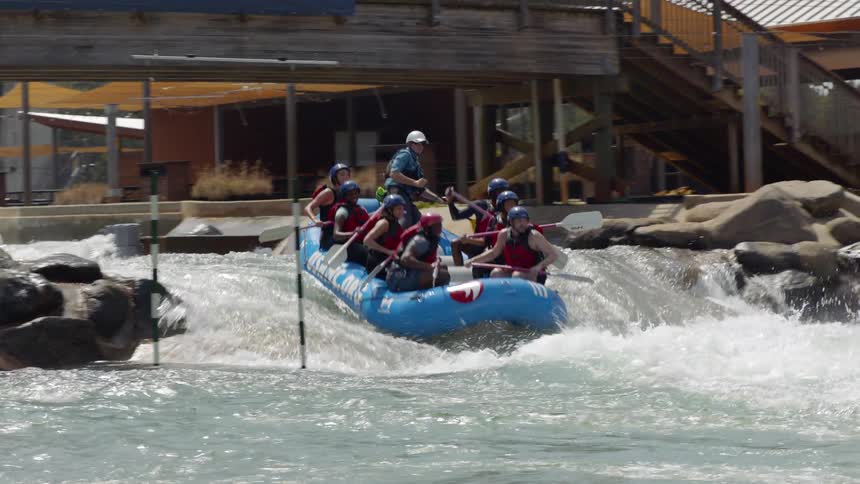 People raft over rapids on a course
