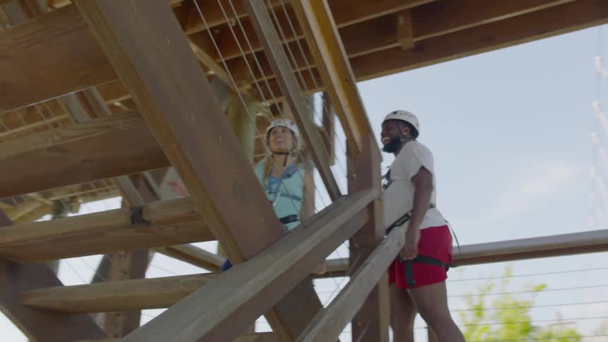 A man and woman wearing helmets and harnesses are climbing a staircase