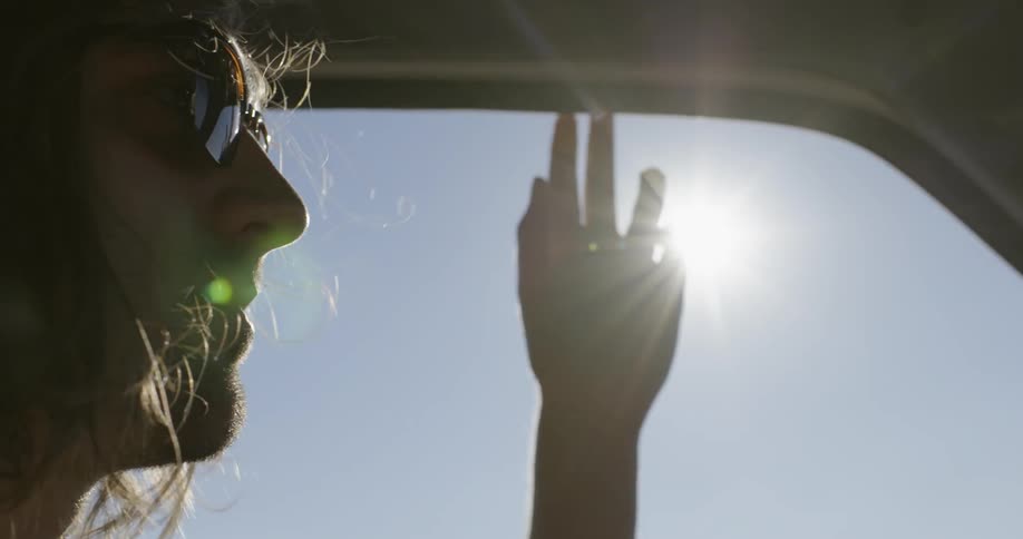 A man drives with his window down on a sunny day