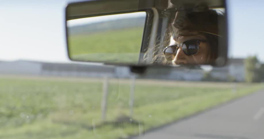 A man is driving down the road on a sunny day