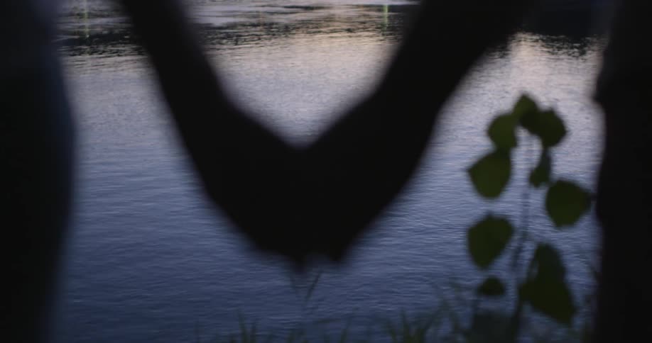 Two people hold hands by the water