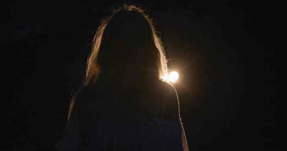 Woman walks towards a light in the dark