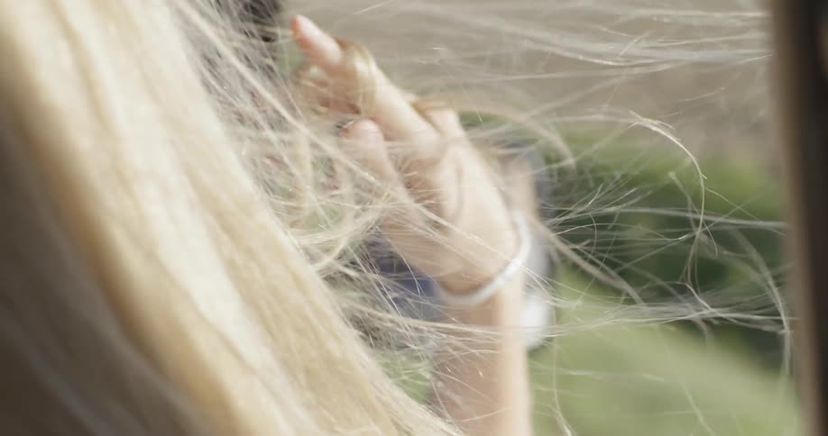 Wind blows through a woman's hair while she rides in a car