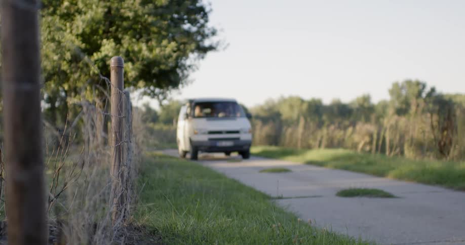Van drives down a small path next to a barbed wire fence