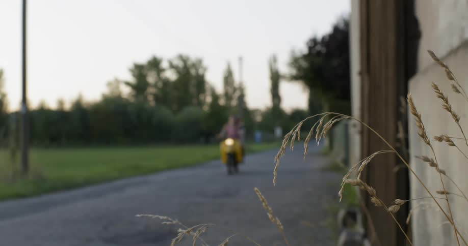 People ride on a small motorbike down a road in the country