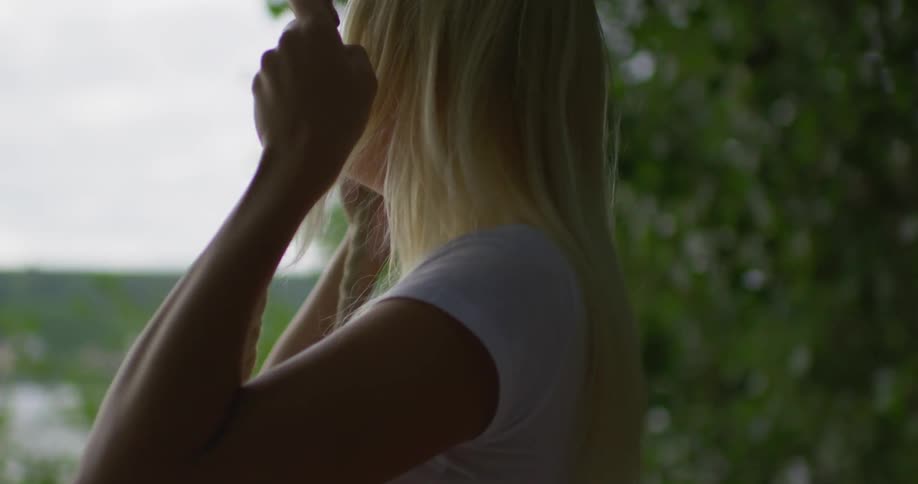 A blond woman swings on a tree swing