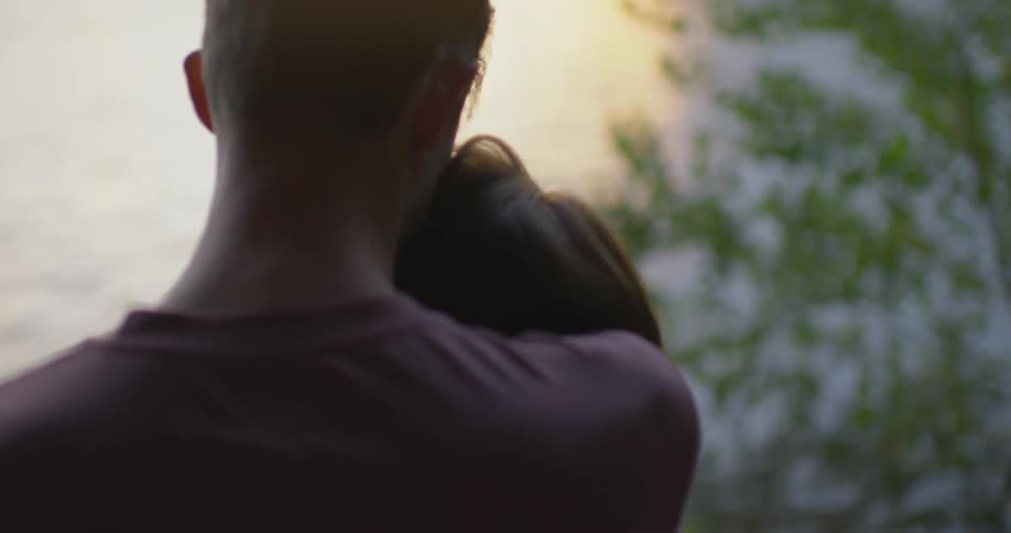 Two people embrace by the water