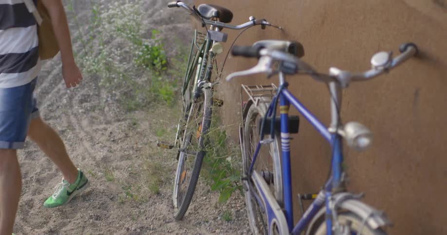 A man leans his bike against a wall