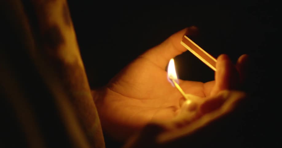 A person blows out a lit match he is holding