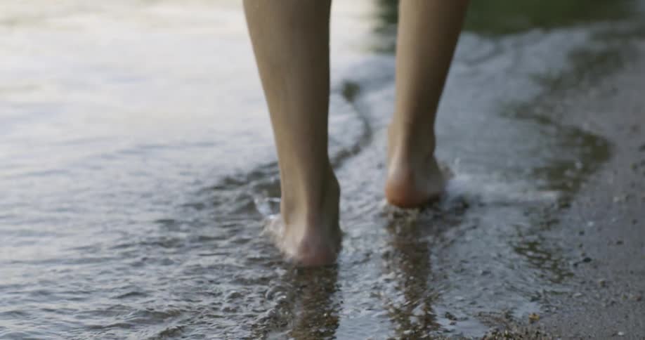 A person is walking in the water near the shore