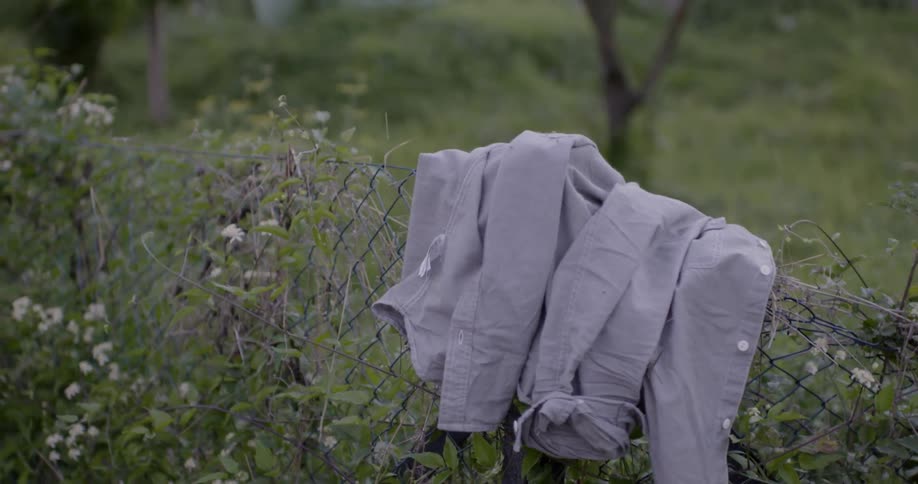 Someone places their jacket on a fence