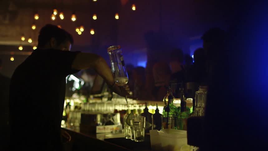 Man pours alcohol into two glasses at a nightclub